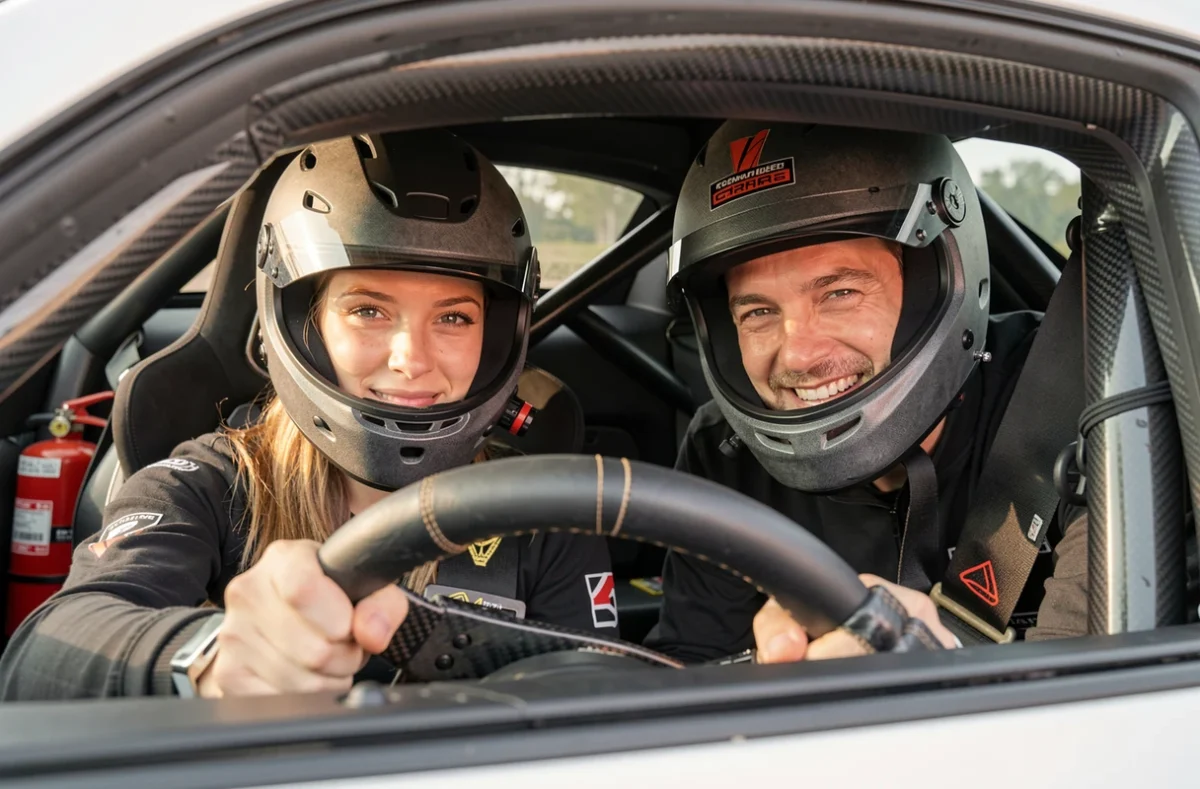 Femme au volant d'une voiture de sport sur circuit avec son partenaire encourageant depuis la fenêtre passager