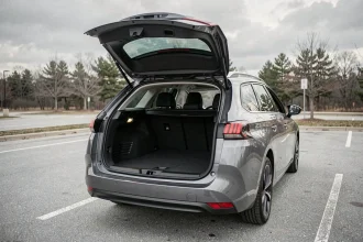 Coffre ouvert de la Peugeot 308 SW avec espace de chargement généreux en vue trois quarts arrière