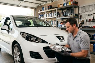Mécanicien examinant un phare de remplacement pour Peugeot 207 dans un garage