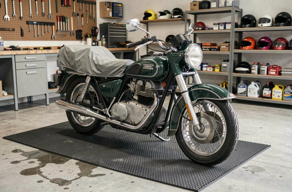 Moto vintage garée sur un tapis de garage épais en caoutchouc pour l'hivernage, demi-couverte d'une housse respirante dans un garage propre