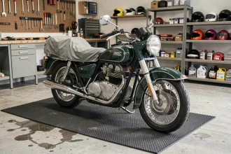 Moto vintage garée sur un tapis de garage épais en caoutchouc pour l'hivernage, demi-couverte d'une housse respirante dans un garage propre