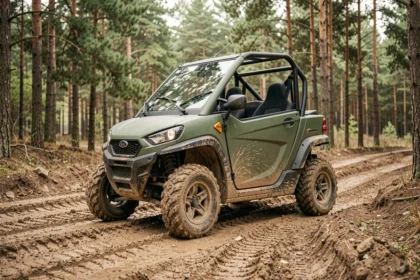 Voiture sans permis 4x4 compacte garée sur un chemin de terre en forêt avec des pneus tout-terrain et une carrosserie verte robuste